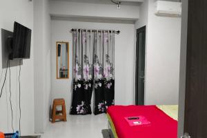 a bedroom with a red bed and a curtain at Riverdale Cikarang by Veto Rooms in Tanahbaru