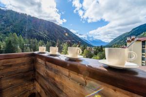 a row of coffee cups on a balcony with mountains at Résidence Grand Roc - Campanules 317 - Happy Rentals in Chamonix-Mont-Blanc +15 photos