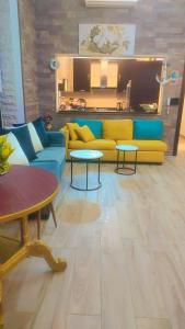 a living room with a yellow couch and two tables at Villa rose 3 in Khirbat Abū Ḩāmid