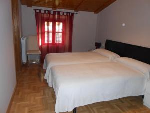 dwa łóżka w pokoju z czerwonym oknem w obiekcie Hospedaje Nuestra Señora de Ujue w mieście Tafalla