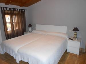 Un dormitorio con una gran cama blanca y una ventana en Hospedaje Nuestra Señora de Ujue, en Tafalla