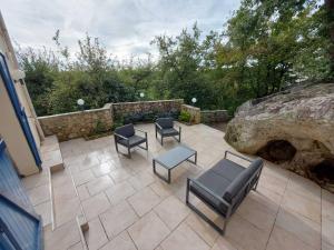 a patio with chairs and tables and a stone wall at Casa Azul in Prunay-sur-Essonnes