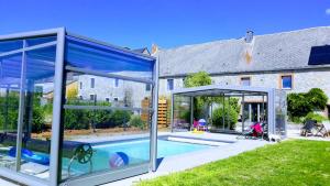 an open glass house with a pool in a yard at Gîtes du tellin in Couvin