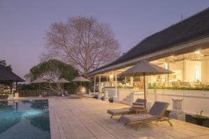 a pool with chairs and umbrellas next to a building at Villa Puri Balangan in Uluwatu