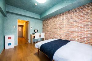 een slaapkamer met een bakstenen muur en een bed bij Portside Avenue in Fukuoka
