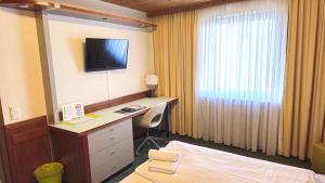 a hotel room with a bed and a desk with a television at Hotel Avenue Altenfurt in Nürnberg
