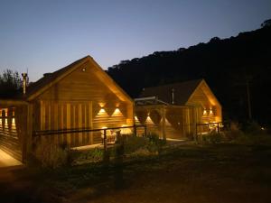 dos graneros de madera de noche con las luces encendidas en Cabana I com Banheira Hidro e Lareira - Chalet Mont Blanc - Urubici, en Urubici