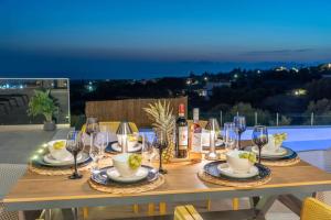 a wooden table with wine glasses and dishes on it at Luxury Villa Gjovana's 2 in Svoronata