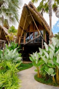 a resort with a thatched building with palm trees at Earth Elements Eco Resort in Ban Bu Hua Chang