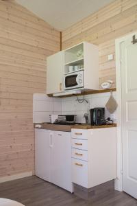 a small kitchen with white cabinets and a microwave at Alingsås Golfklubb in Alingsås