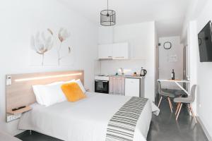 a white bedroom with a bed and a kitchen at MAGNOLIA SUITES in Nafpaktos