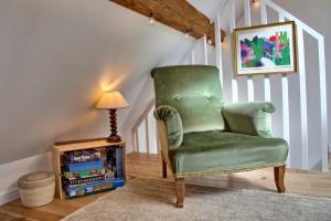a green chair in a room with a lamp at Gîte le Grenier GRAY in Gray
