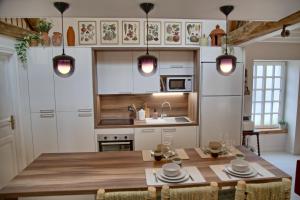 a kitchen with a wooden table and a kitchen with white cabinets at Gîte le Grenier GRAY in Gray