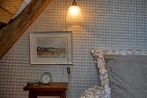 a bedroom with a bed and a clock on a table at Gîte le Grenier GRAY in Gray
