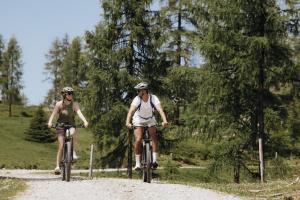 two people riding bikes on a dirt road at Hotel Dorfer in Grossarl