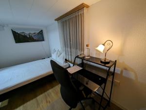a bedroom with a desk and a bed with a window at Privatzimmer in Buttisholz - Luzern in Buttisholz