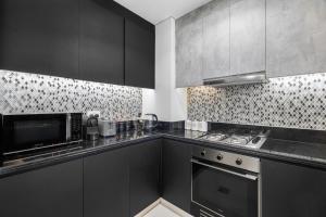 a kitchen with black cabinets and a microwave at 64th floor Skyline Pool with Burj Khalifa View in Paramount Hotel Midtown in Dubai