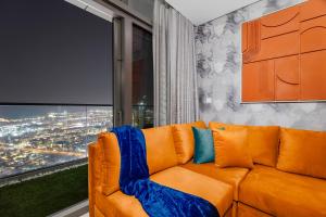 an orange couch in a room with a large window at 64th floor Skyline Pool with Burj Khalifa View in Paramount Hotel Midtown in Dubai