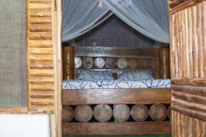 ein Etagenbett aus Holz mit einem Bett aus Baumstämmen in der Unterkunft Charming Cottage in Chumani, Kilifi County in Roka