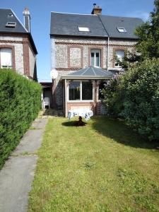 a dog sitting in the grass in front of a house at Gite en bord de mer en Normandie in Saint-Pierre-en-Port