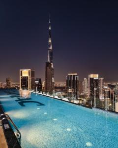 a swimming pool with a city skyline at night at 64th floor Skyline Pool with Burj Khalifa View in Paramount Hotel Midtown in Dubai