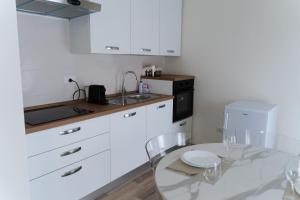 a kitchen with white cabinets and a glass table at ComfortHome Fiera in Cornaredo +13 photos