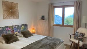 a bedroom with a bed with a window and a chair at Le Lézard et la Grenouille BnB in Ovronnaz