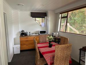 a dining room with a table and chairs and a kitchen at Gully Retreat in Hamilton