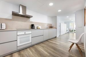 a kitchen with white cabinets and a white chair at Albercutx Pollentia 1 2 3 in Port de Pollensa