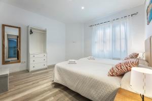a white bedroom with a bed and a mirror at Albercutx Pollentia 1 2 3 in Port de Pollensa