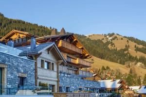 a building with a mountain in the background at Super Luxury Serviced Apartment next to Gstaad in Rougemont