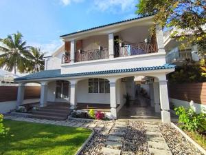 a white house with a balcony and a yard at Beach Hive in Blue Bay