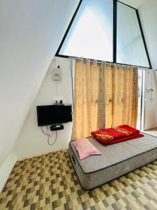 una cama en una habitación con una ventana grande en TULDA BAMBUSA RESORT, en Kāziranga