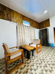 sala de estar con muebles de madera, mesa y sillas en TULDA BAMBUSA RESORT, en Kāziranga