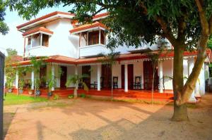 una casa bianca con un albero di fronte di Punchi Walawwa - Guest House - Holiday Bungalow a Anuradhapura