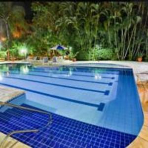 a large swimming pool with blue tiles on it at Flat Amarilis Riviera de São Lourenço - Flat Lindo com Varanda in Riviera de São Lourenço