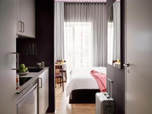 a bedroom with a bed and a kitchen with a window at Mekano Apartment Hotel in Copenhagen
