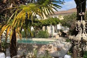 a house with a swimming pool and a palm tree at Guest house with charm, Le figuier in Vignonet