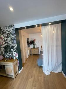 een woonkamer met een wit gordijn en een houten vloer bij la maison d' antoine 2 in Chamalières