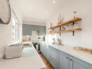 una cocina con armarios azules y un reloj en la pared en Edie' Bungalow, en Bridlington 7 fotos más
