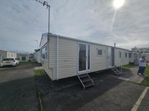 a man is standing next to a mobile home at Ruby a modern caravan in Rhyl in Rhyl