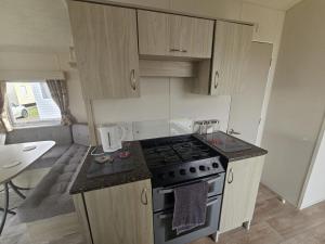 a kitchen with a stove and a counter top at Ruby a modern caravan in Rhyl in Rhyl +4 photos