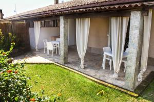 a patio with white curtains and a table and chairs at Domu Virginia in Castiadas