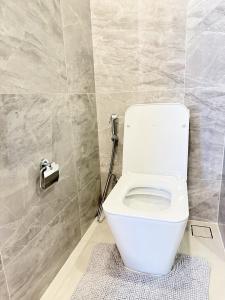 a white toilet in a bathroom with a tile wall at 1BR l 10 Mins from Siam Paragon l Rooftop Pool in Bangkok +7 photos