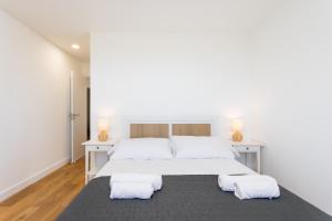 ein weißes Schlafzimmer mit einem großen Bett und zwei Handtüchern in der Unterkunft EDEN RENTALS Luxury Heated-Pool Villa El Sauzal in El Sauzal