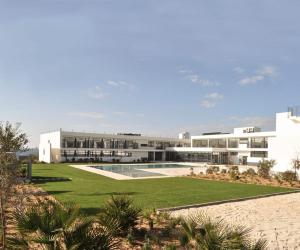 a building with a swimming pool in front of it at Porto Covo Praia Hotel & SPA in Porto Covo