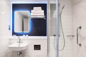 a bathroom with a sink and a shower with a mirror at Strand Palace in London