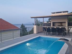a swimming pool on a patio with a table and a fireplace at Apartman Mimi in Prigradica