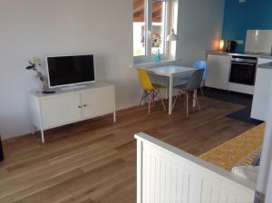 a living room with a television and a table with chairs at Schlaf aus im Schwedenhaus in Eimeldingen
