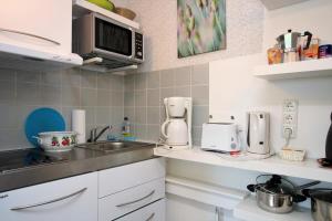 una cocina con fregadero y microondas en Teewelkenhüs Wiesenappartement, en Archsum